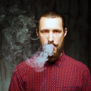 A man blowing a smoke cloud out of his mouth