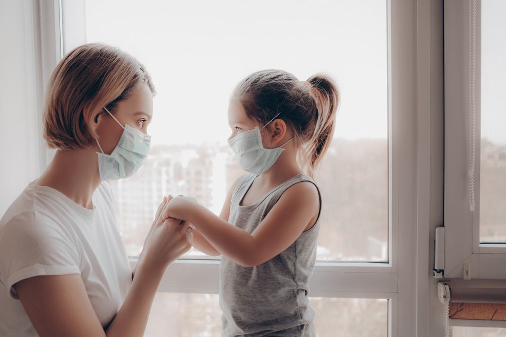 Mom and daughter holding hands and wearing masks